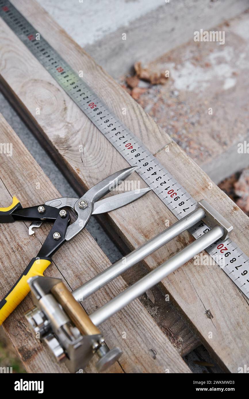 fotografia dell'oggetto di nuove pinze metalliche posizionate accanto al metro su un tavolo di legno all'esterno del sito Foto Stock