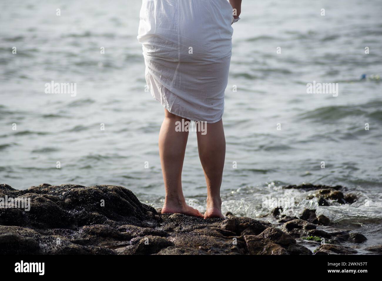 Parte inferiore delle gambe di persone non identificate sulla spiaggia. Omaggio a Iemanja. Foto Stock