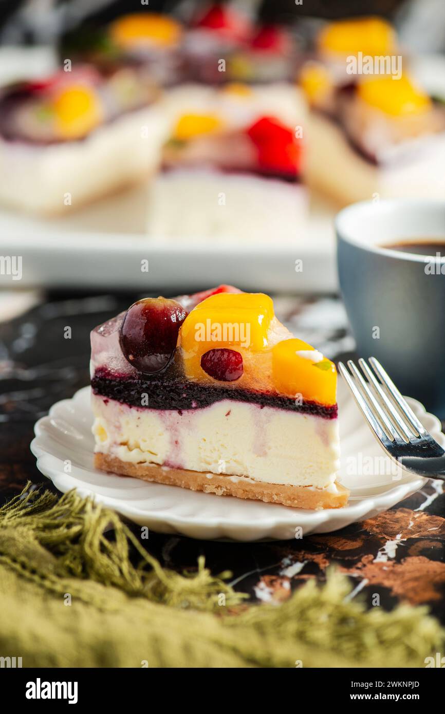 Cheesecake deliziosa e leggera senza cottura con frutta estiva, tra cui fragole, mango e uva. Foto Stock