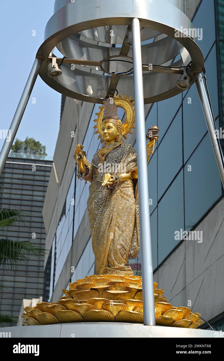 Lakshmi è una delle principali dee dell'induismo, raffigurata qui come un'elegante donna di colore dorato in piedi su un loto in un santuario di Bangkok Foto Stock