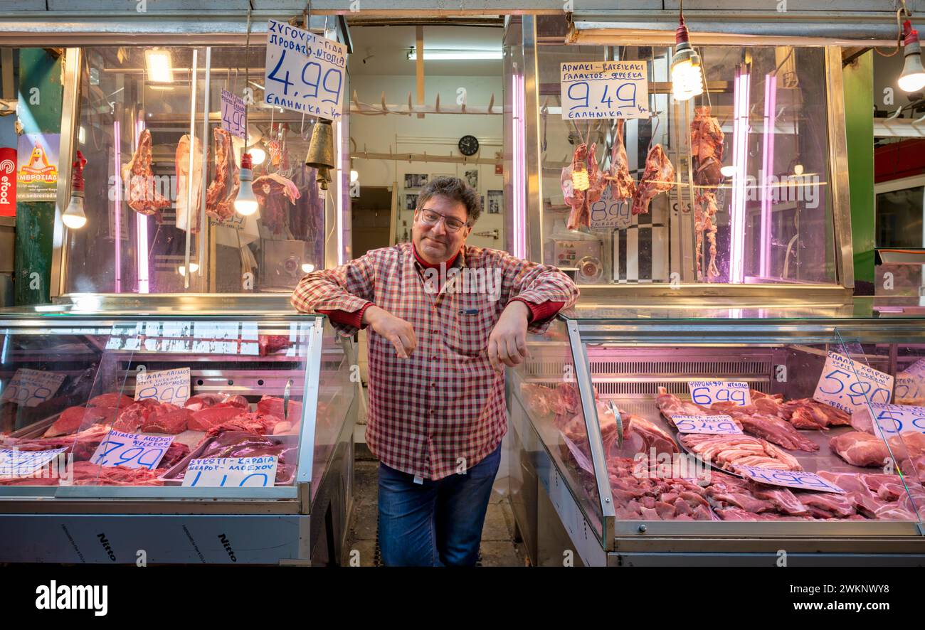 Macellaio, commerciante di carne che si posa orgogliosamente davanti al suo bancone, esposizione di carni fresche, macelleria, cibo, mercato Kapani, Vlali, Salonicco Foto Stock