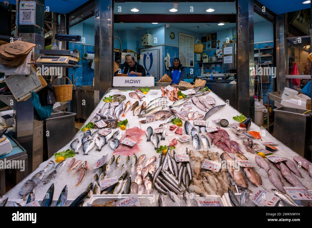 Commerciante, pescivendolo che lavora nel suo banco di vendita, esposizione di pesce fresco e frutti di mare sul ghiaccio, cibo, mercato Kapani, Vlali, Salonicco, Macedonia, Grecia Foto Stock