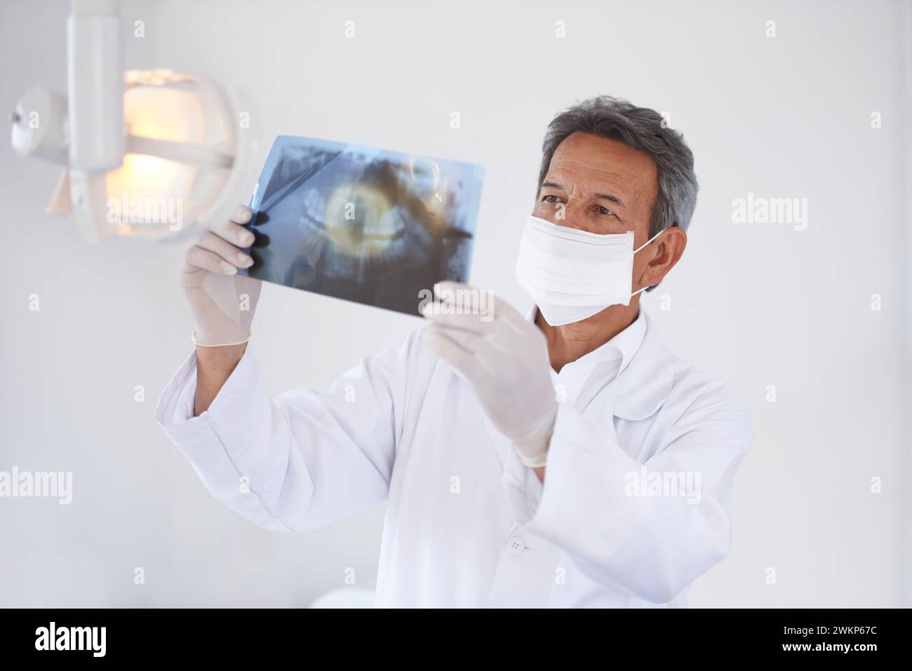 Dentista anziano, uomo e raggi x di denti per chirurgia dentale, assistenza sanitaria e salute orale con maschera facciale in clinica. Medico con analisi di Foto Stock