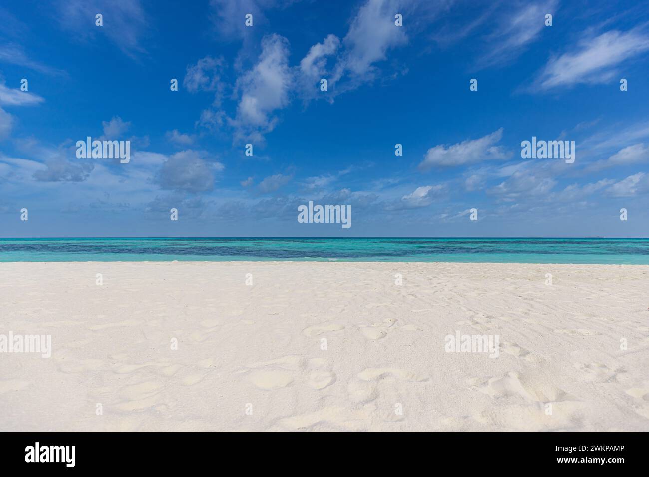 Spiaggia astratta sullo sfondo del mare. Sabbia bianca soleggiata, cielo blu e calmo paesaggio tropicale. Concetto di costa costiera con natura esotica Foto Stock