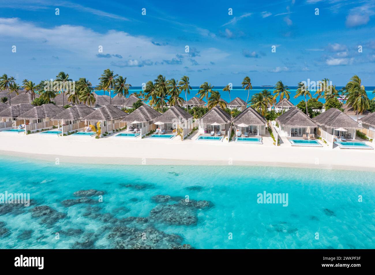 Foto aerea delle splendide ville delle Maldive paradisiache ai tropici. Costa incredibile, acqua blu turchese, palme e spiaggia di sabbia bianca. Viaggi di lusso Foto Stock