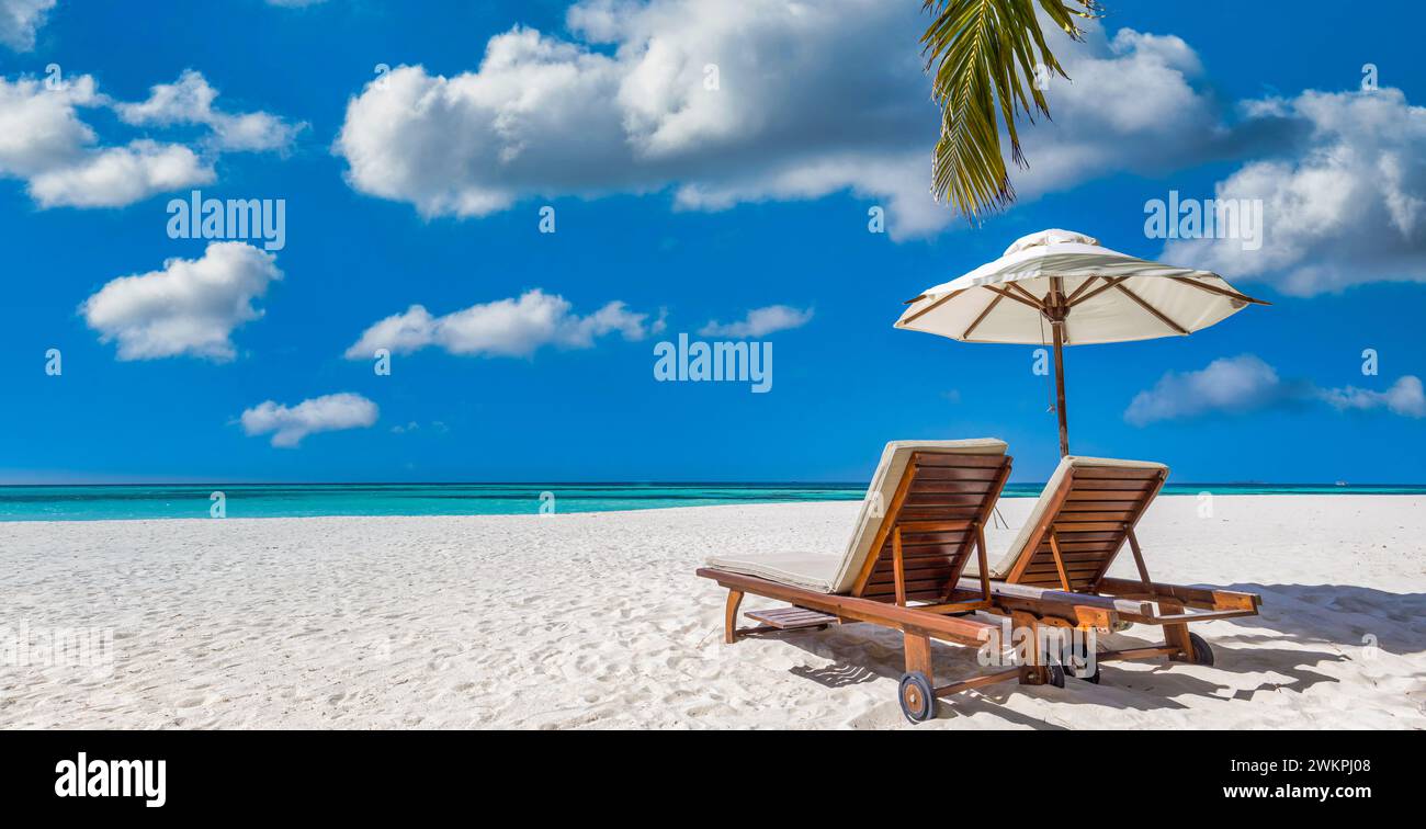 Bellissimo cielo panoramico di sabbia marina. Spiaggia tropicale rilassante, soleggiato paesaggio estivo dell'isola. Amore coppia sedie ombrello palma lascia romantica costa. Lusso Foto Stock