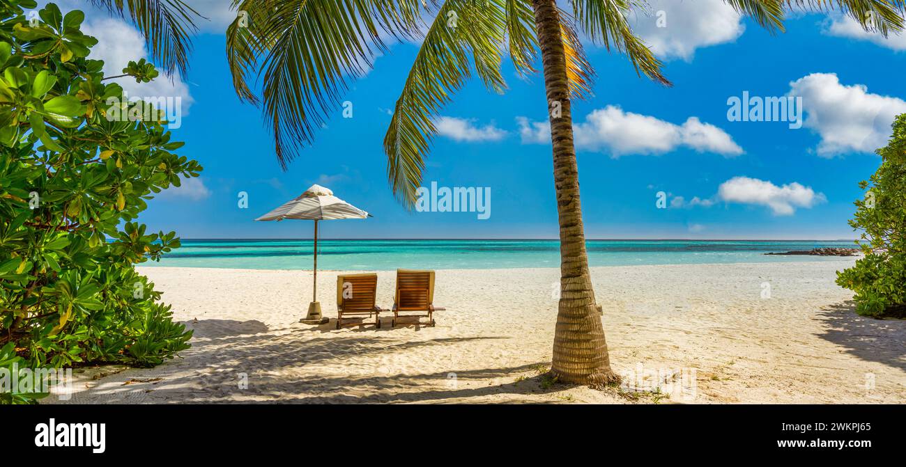 Bellissimo cielo panoramico di sabbia marina. Spiaggia tropicale rilassante, soleggiato paesaggio estivo dell'isola. Amore coppia sedie ombrello palma lascia romantica costa. Lusso Foto Stock