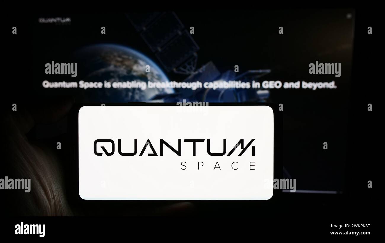 Persona che possiede uno smartphone con il logo della società aerospaziale statunitense Quantum Space LLC davanti al sito Web. Mettere a fuoco il display del telefono. Foto Stock