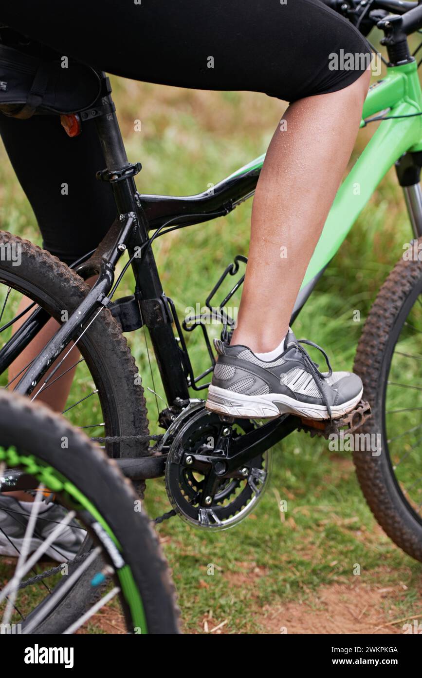 Persona, gambe e ciclista con bicicletta in natura per remare, ciclismo o sport all'aperto in salute e benessere. Primo piano di motociclisti, piedi o scarpe Foto Stock