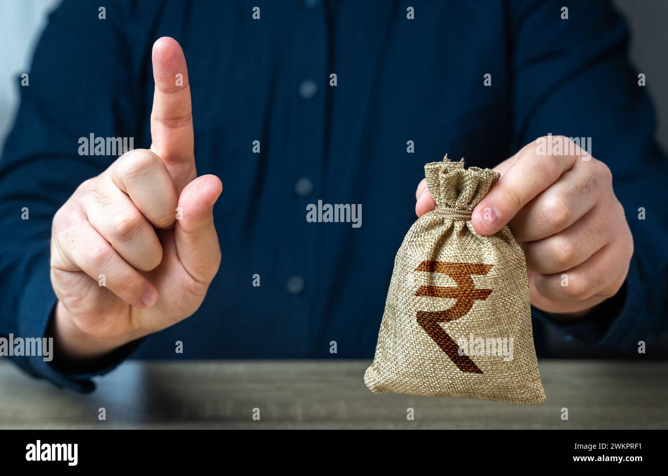 Un uomo avverte con il dito offrendo un sacco di soldi per rupie indiane. Finanziamenti e sovvenzioni. Banche e finanza. Cattiva storia del credito. Condizioni rigorose. Prestito per Foto Stock