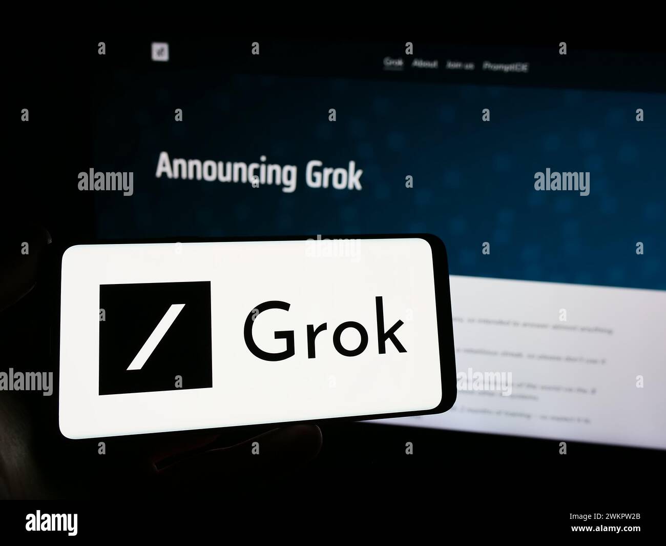 Persona con smartphone con logo del chatbot di intelligenza artificiale generativa Grok (X.ai) davanti al sito Web. Mettere a fuoco il display del telefono. Foto Stock