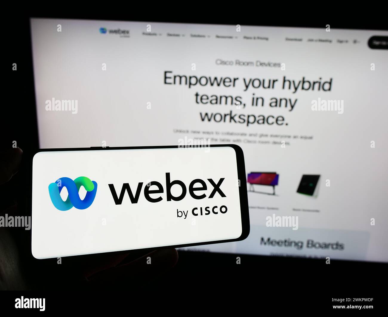 Persona che detiene un cellulare con il logo della società statunitense di comunicazioni unificate Webex by Cisco davanti alla pagina Web aziendale. Mettere a fuoco il display del telefono. Foto Stock