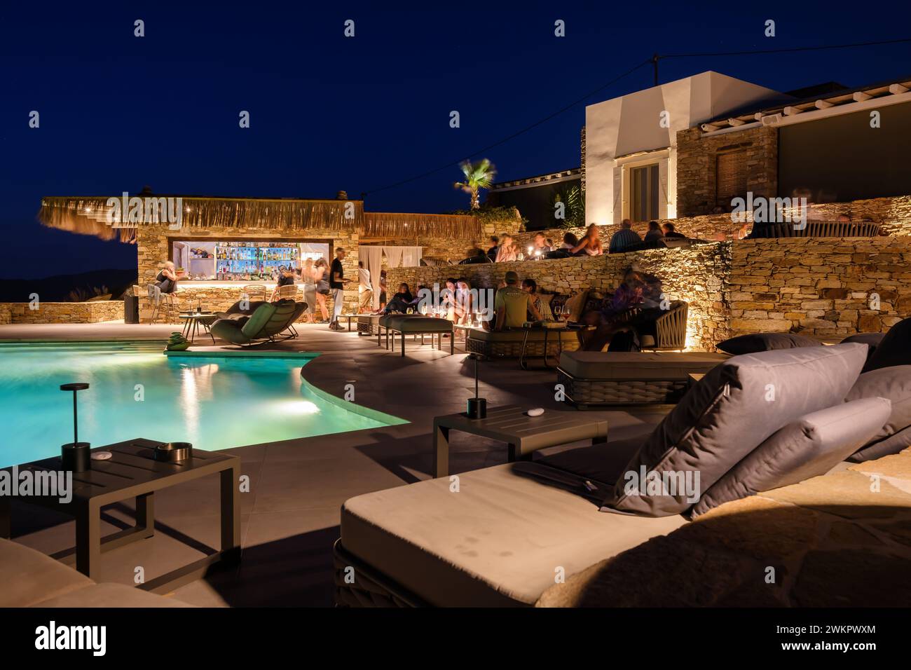 IOS, Grecia - 17 settembre 2023: Veduta di varie persone sedute di fronte ad una piscina presso un lounge bar che si gode il tramonto a iOS Grecia Foto Stock
