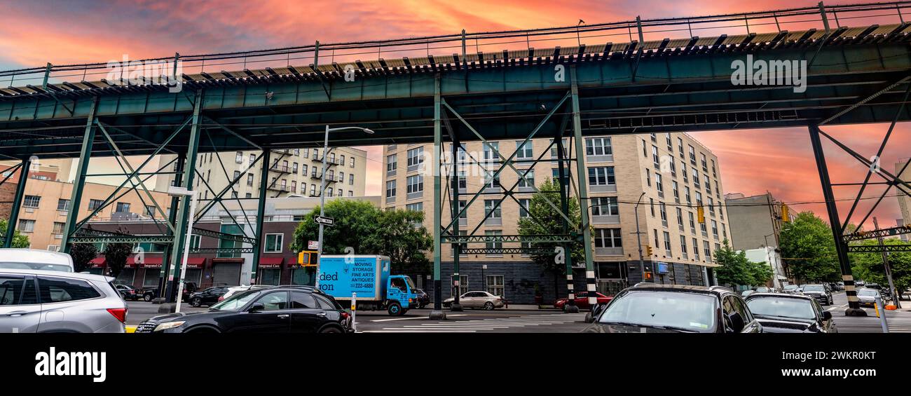 New York, USA; 3 giugno 2023: Tipici binari del treno sopraelevato e del tram del Bronx, un quartiere nella grande Mela, sotto un cielo arancione all'alba. Foto Stock