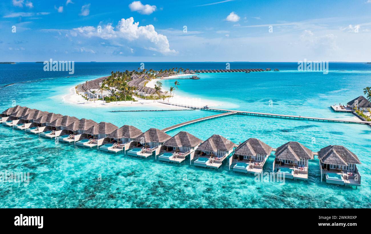 Tranquillo paesaggio aereo, lussuose ville tropicali sull'acqua. Bellissima spiaggia di palme sull'isola cielo soleggiato. Stupendi occhi d'uccello, viste panoramiche delle Maldive Foto Stock