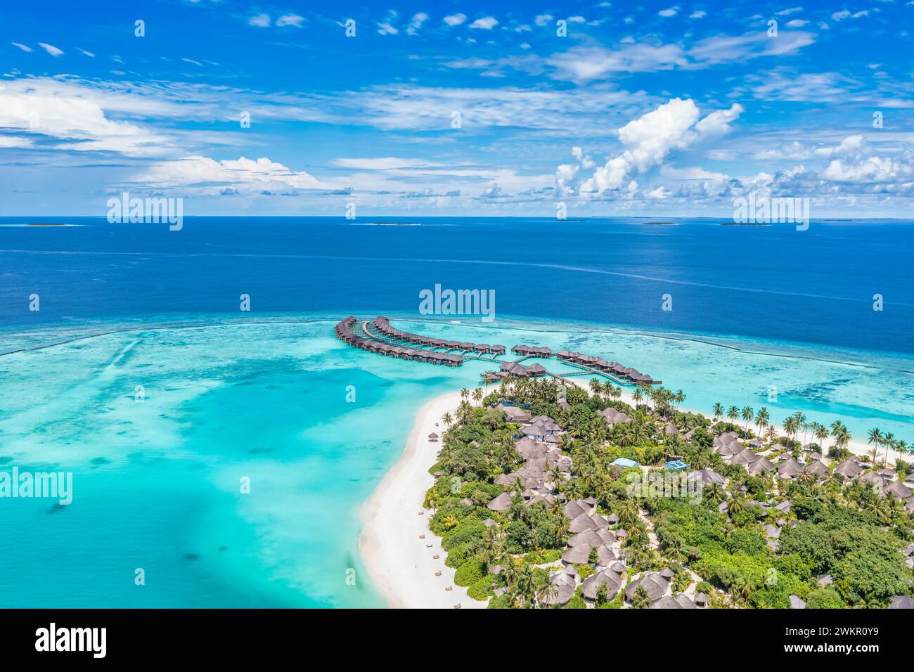 Tranquillo paesaggio aereo, lussuose ville tropicali sull'acqua. Bellissima spiaggia di palme sull'isola cielo soleggiato. Stupendi occhi d'uccello, viste panoramiche delle Maldive Foto Stock