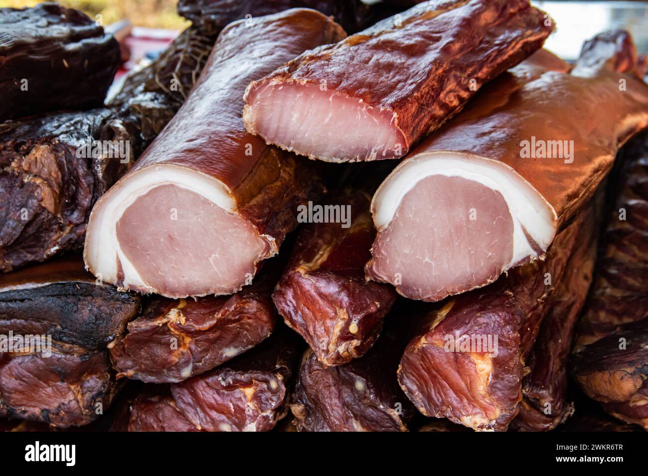 Deliziosi pezzi di carne affumicata esposti per la vendita nel mercato presentato in vendita in un mercato agricolo nel villaggio di Kacarevo, festival del bacon gastronomico Foto Stock