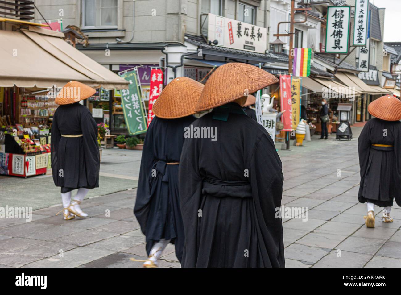 Nagano, Giappone. Monaci buddisti Zen giapponesi della scuola Soto con cappelli Kasa che guardano la porta Sanmon di Zenko-ji, un tempio buddista Foto Stock