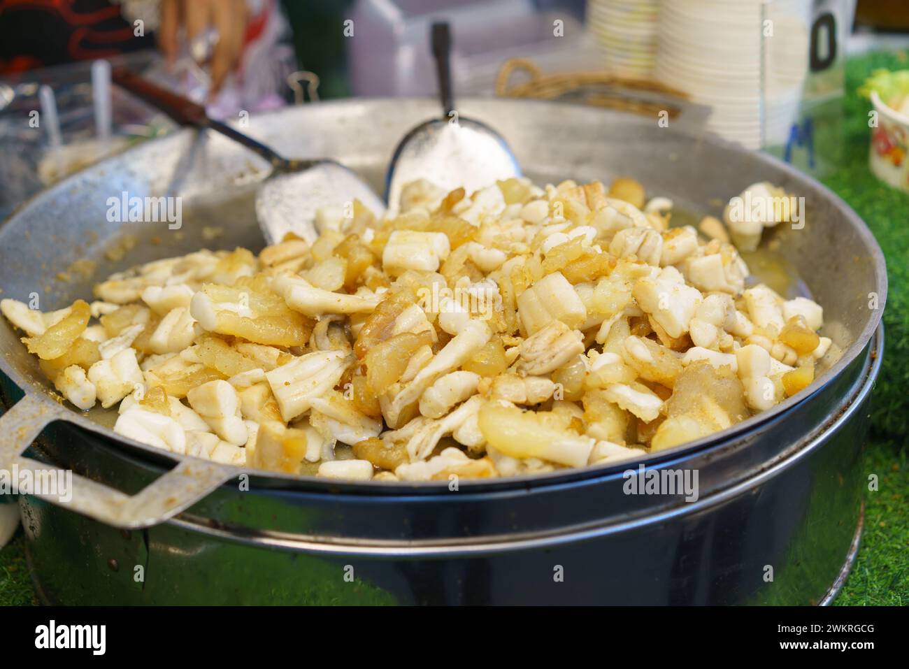 Il calamaro fresco viene fritto alla perfezione in una grande padella in un vivace mercato di Street food, uno spuntino popolare tra la gente del posto e i turisti Foto Stock