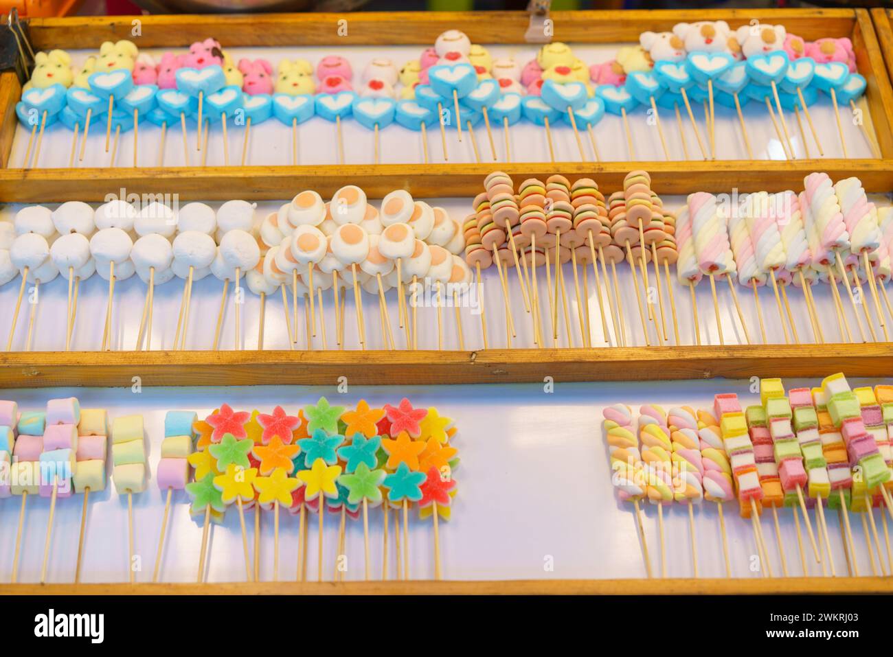 Una deliziosa selezione di coloratissimi spiedini di caramelle, tra cui marshmallow e caramelle in gelatina, esposti in un bancone del mercato in vendita Foto Stock