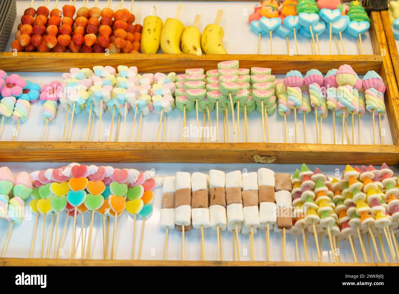 Una deliziosa selezione di coloratissimi spiedini di caramelle, tra cui marshmallow e caramelle in gelatina, esposti in un bancone del mercato in vendita Foto Stock