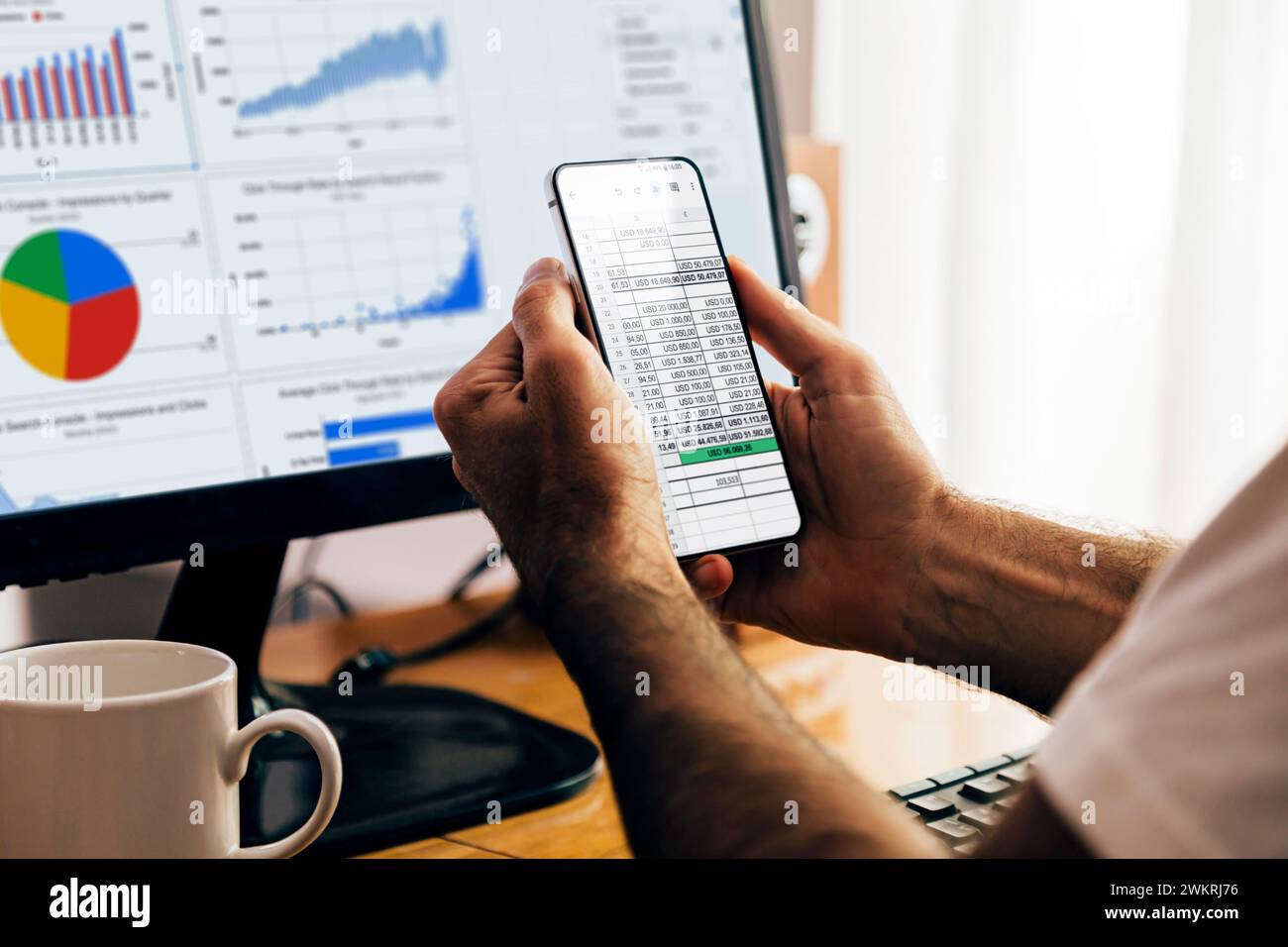 Uomo che utilizza l'app fogli su un telefono cellulare e un computer portatile. Google Workspace, strumenti di produttività digitale online. Uso del foglio di calcolo. Foto Stock