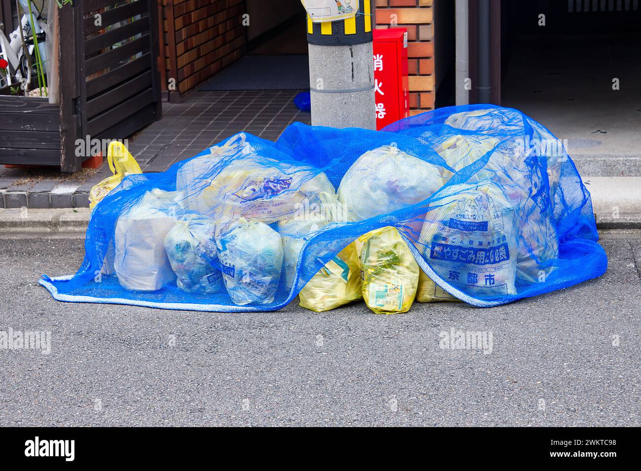Sacchetti con spazzatura per strada protetti da una rete in attesa della raccolta Foto Stock