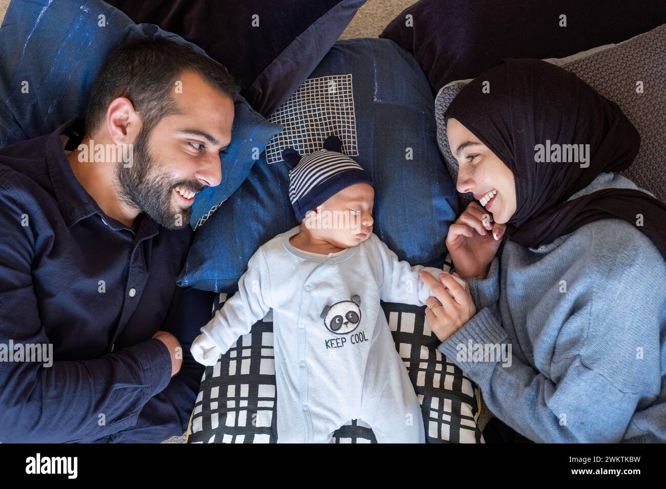 I genitori musulmani arabi condividono un momento tenero con la loro figlia appena nata, irradiando amore e gioia nella loro casa. Foto Stock