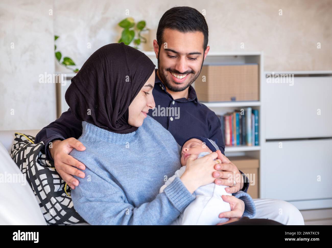 I genitori musulmani arabi condividono un momento tenero con la loro figlia appena nata, irradiando amore e gioia nella loro casa. Foto Stock