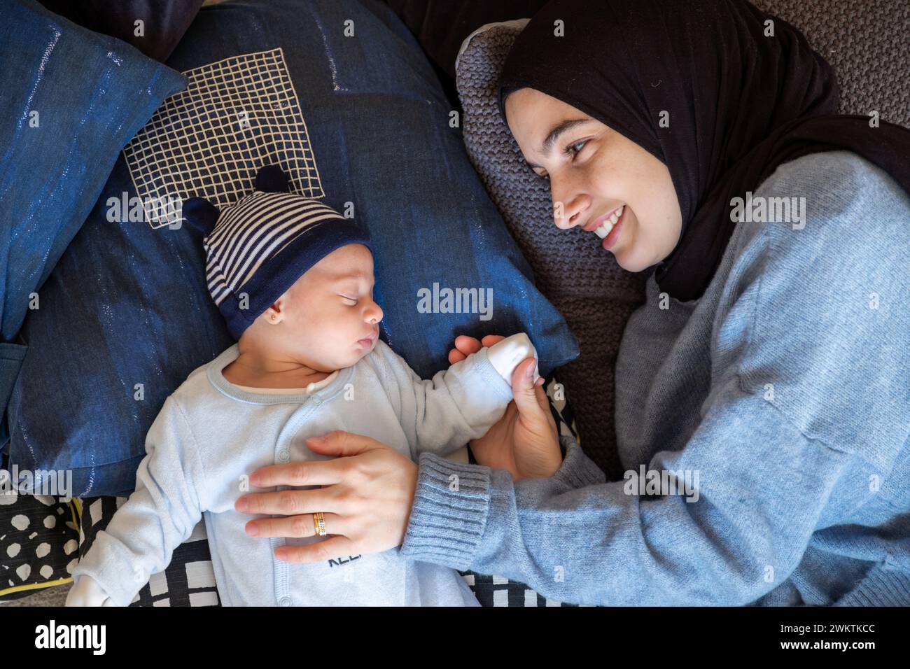 I genitori musulmani arabi condividono un momento tenero con la loro figlia appena nata, irradiando amore e gioia nella loro casa. Foto Stock
