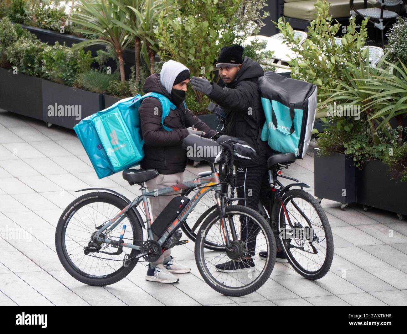 Deliveroo consegna di cibo ciclisti che discutono le indicazioni stradali in London Street Foto Stock