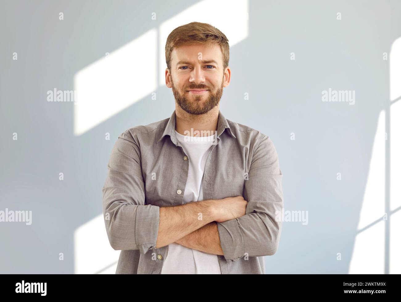 Ritratto di un uomo bello e sicuro di sé in piedi con le braccia incrociate Foto Stock