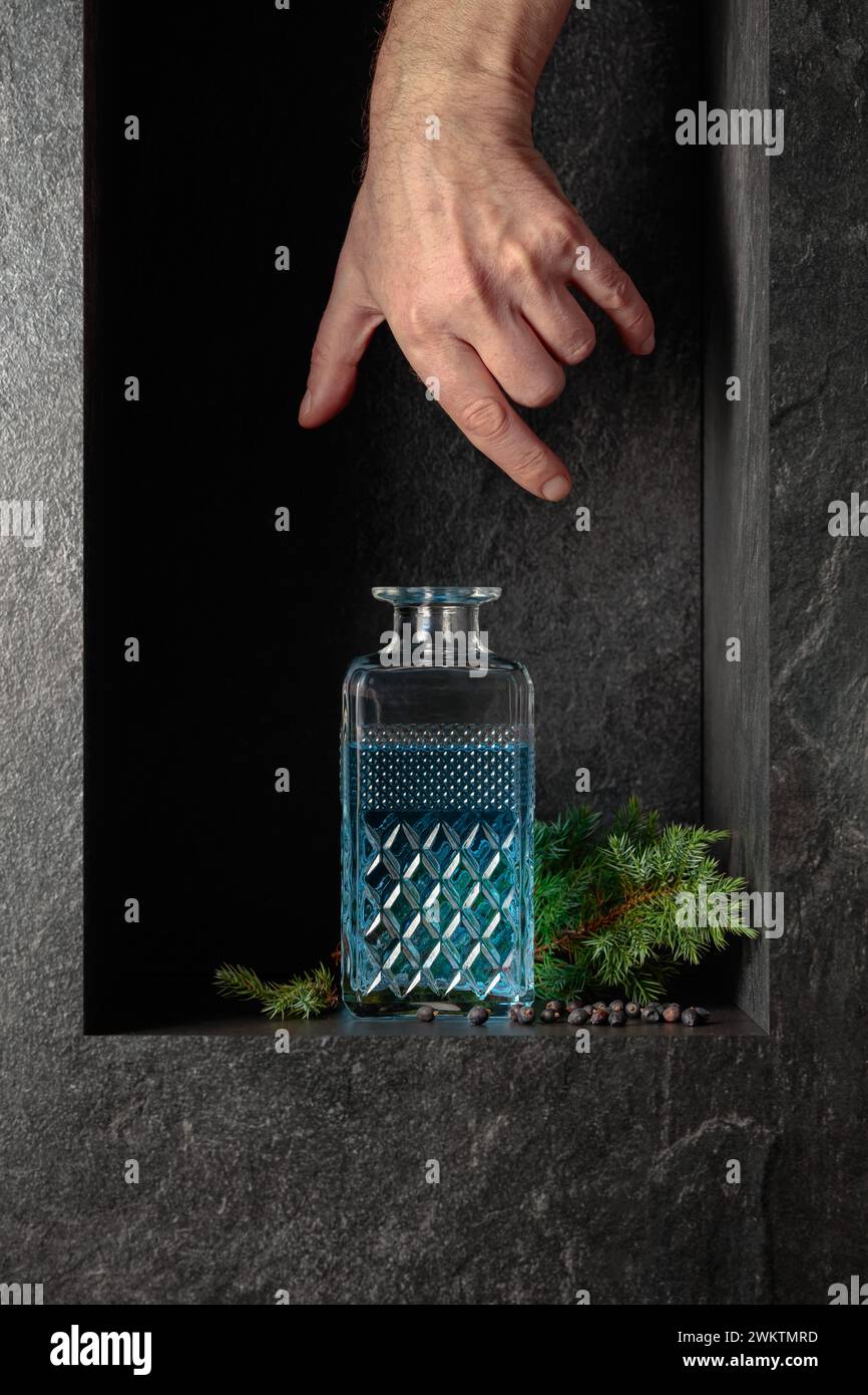 Sbraccio a mano per un decanter di gin. Un'immagine concettuale sul tema delle bevande costose. Foto Stock