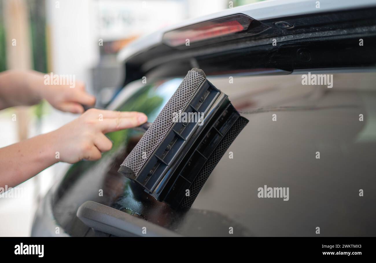 Lavoratore maturo che pulisce il parabrezza dell'auto con il panno in spugna. Foto Stock