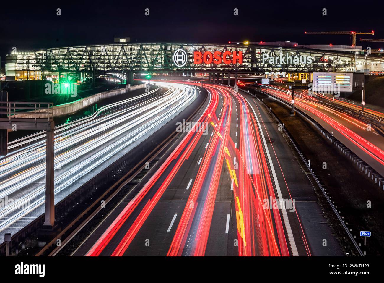 Autobahn A8 Flughafen Stuttgart mit Bosch-Parkhaus. Die 440 metri bietet lange Konstruktion 4200 Fahrzeugen Platz. Bosch HAT Die Namensrechte, der stilisierte Zündanker misst 12 Meter im Durchmesser. Damit ist es eine der größten Leuchtreklamen der Welt. // 04.05.2024: Stoccarda, Baden-Württemberg, Deutschland. *** Superstrada A8 all'aeroporto di Stoccarda con parcheggio a più piani Bosch la struttura lunga 440 metri offre spazio per 4.200 veicoli Bosch ha i diritti di denominazione, l'ancora di accensione stilizzata misura 12 metri di diametro questo la rende una delle più grandi insegne illuminate del mondo Foto Stock