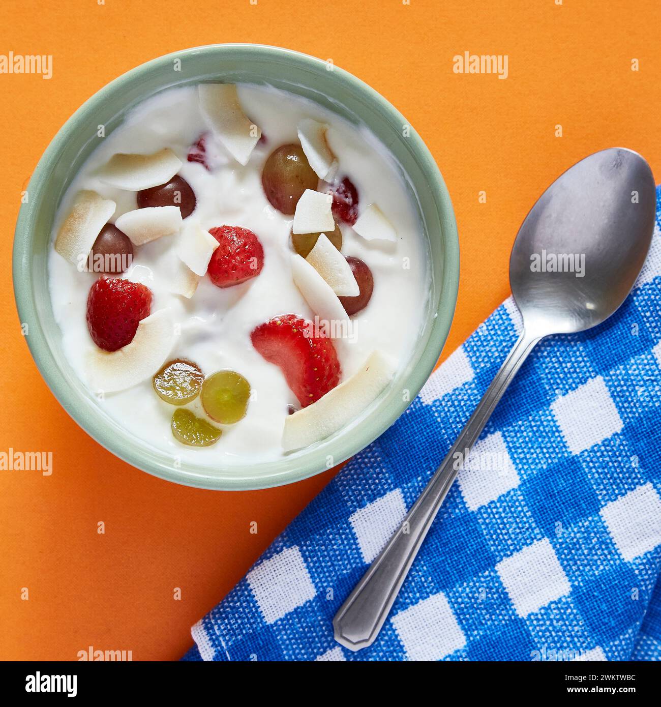 Una ciotola di yogurt con frutta su sfondo arancione e scacchi Foto Stock