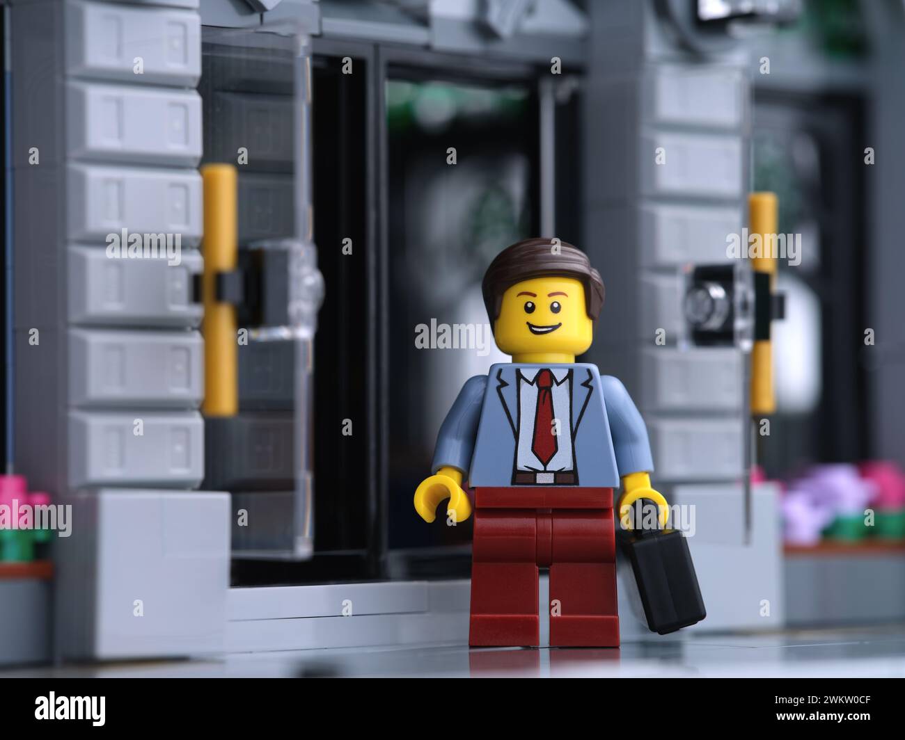 Tambov, Federazione Russa - 20 febbraio 2024 Una minifigura d'affari Lego in piedi davanti a una banca mentre tiene in mano una valigia. Foto Stock