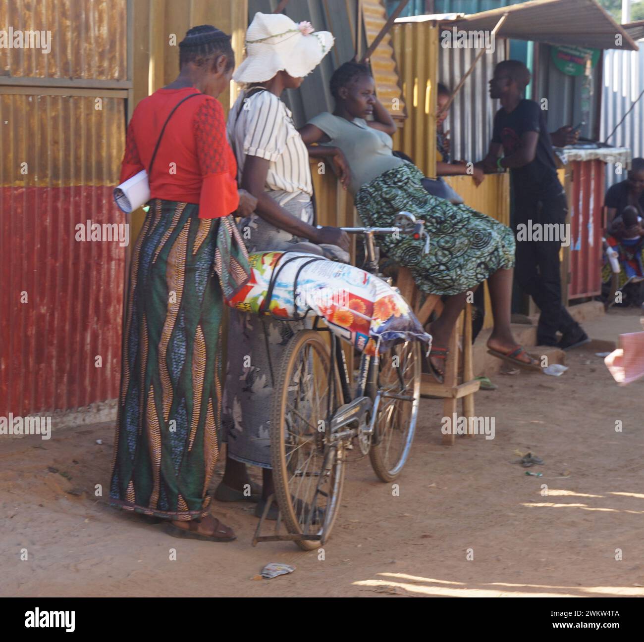 Mpongwe, Zambia. 16 febbraio 2024. Le donne si trovano accanto a una bicicletta carica di merci a Mpongwe, provincia di Copperbelt, Zambia, il 16 febbraio 2024. Nel corso degli anni, le biciclette sono emerse come un catalizzatore per il cambiamento, offrendo nuova indipendenza, opportunità e libertà a molte donne e ragazze nello Zambia rurale. Crediti: Lillian banda/Xinhua/Alamy Live News Foto Stock