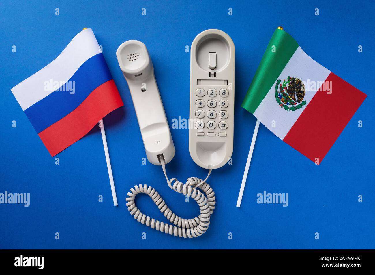Vecchio telefono e bandiere di Russia e Messico su sfondo blu, concetto sul tema delle conversazioni telefoniche tra i paesi Foto Stock
