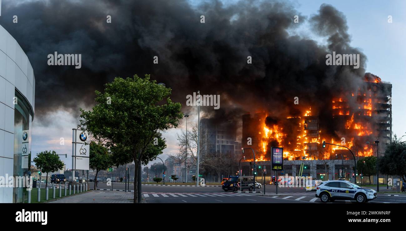 Vista panoramica di un grande edificio residenziale in fiamme, che brucia al suolo nella città di Valencia con servizi di emergenza che circondano la zona Foto Stock