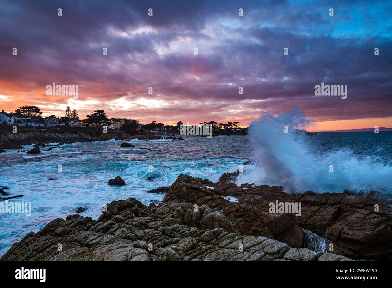 L'alta surf si schianta contro le rocce al tramonto sopra Lover's Point, Pacific Grove, California Foto Stock