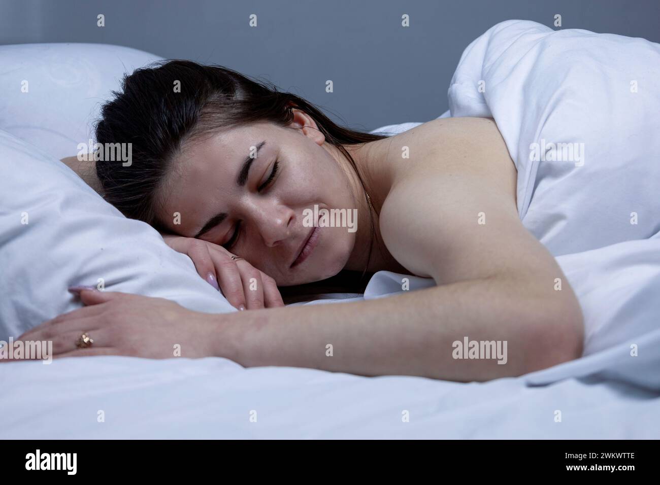 La ragazza dorme in un letto bianco Foto Stock