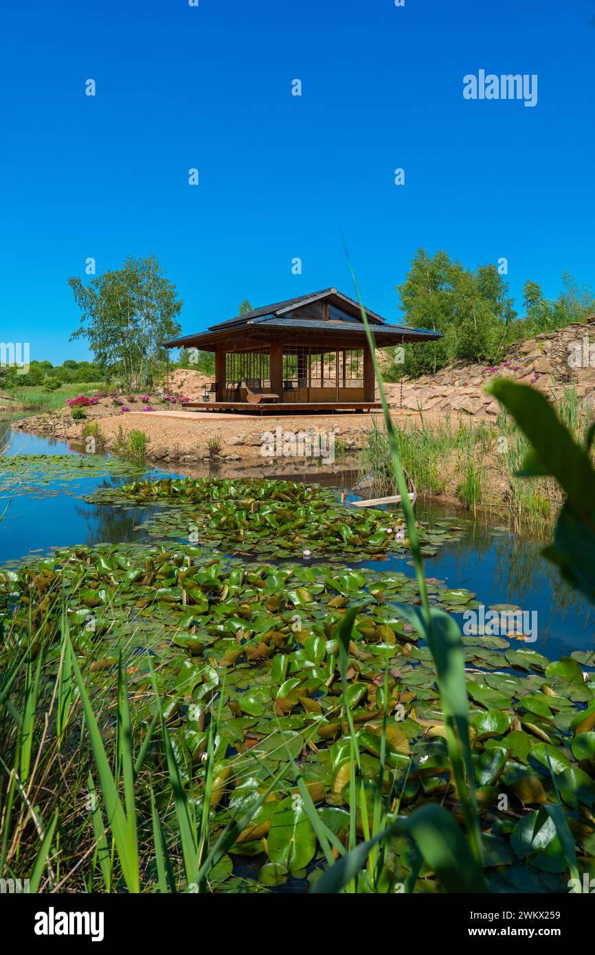 Gazebo in stile giapponese. Luogo della cerimonia del tè. Casa da tè giapponese vicino a uno stagno con ninfee e salici. Foto Stock