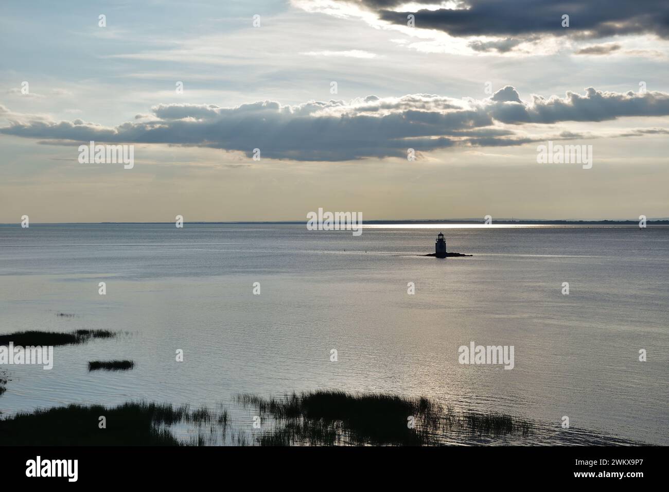 Faro nel mezzo del fiume San Lorenzo al tramonto. La luce solare viene filtrata attraverso le nuvole per un effetto spettacolare. Solitudine e momento di pace. Foto Stock