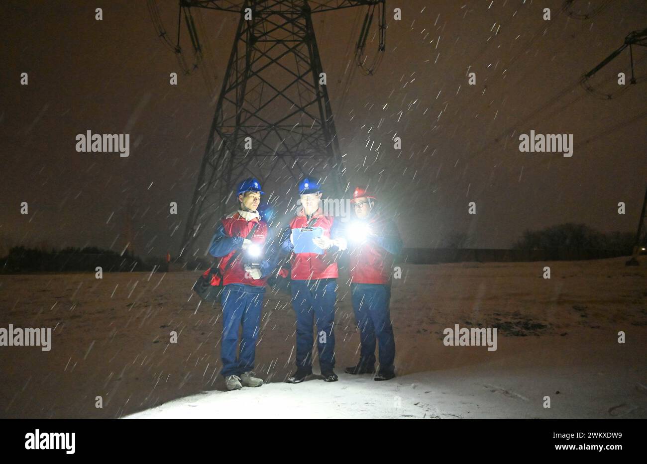 CHUZHOU, CINA - 22 FEBBRAIO 2024 - gli operai elettrici sfidano le basse temperature nella neve per ispezionare la linea di trasmissione cross-City da 500 kilovolt e. Foto Stock