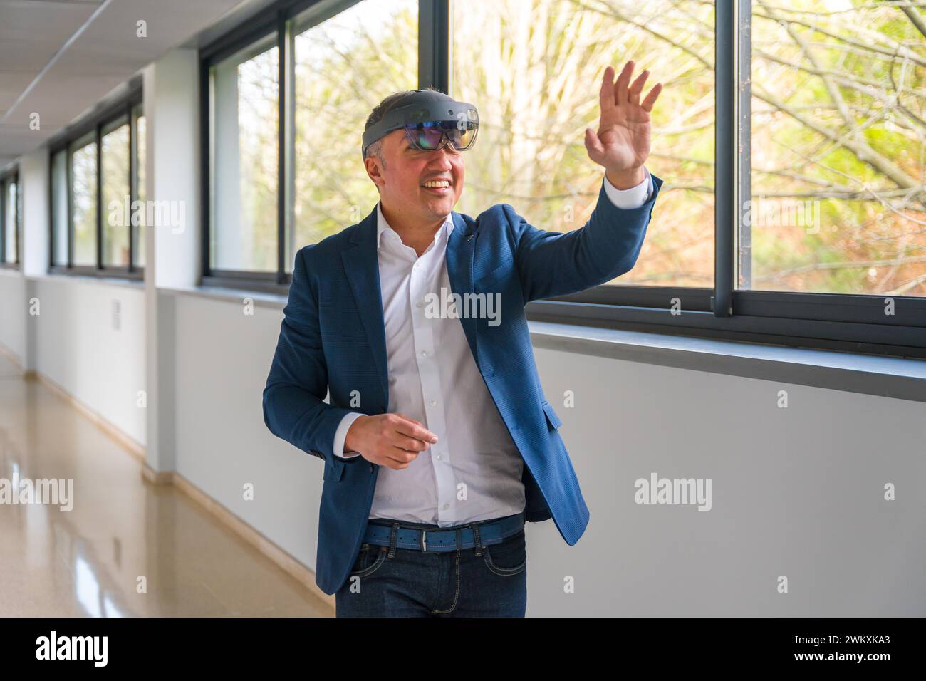 Uomo d'affari maturo e informale che utilizza un simulatore di realtà virtuale nel corridoio di un edificio Foto Stock