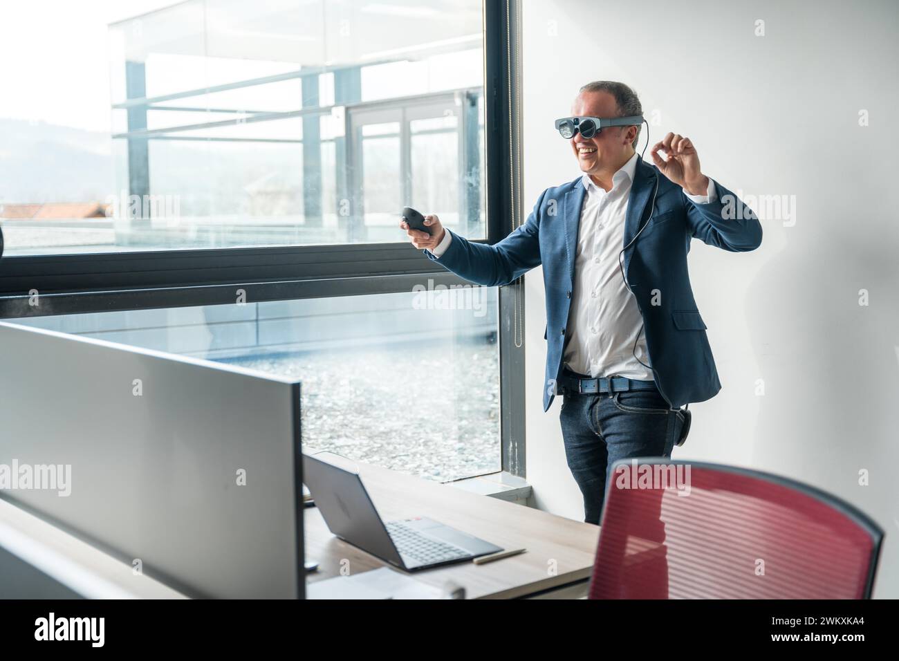 Uomo d'affari che si diverte a testare nuovi occhiali per la realtà mista in ufficio Foto Stock