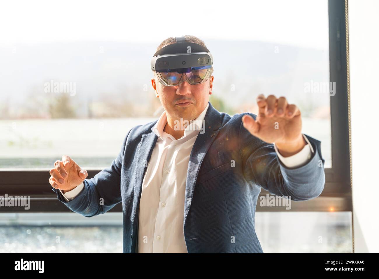 Vista frontale di un uomo d'affari che indossa occhiali di protezione per la realtà mista che toccano lo schermo interattivo in ufficio Foto Stock