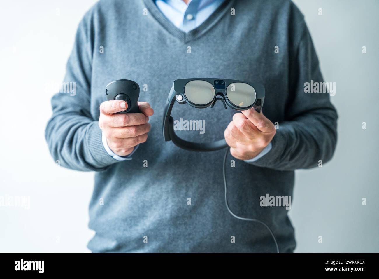 Foto in studio con primo piano delle mani di un uomo con telecomando e occhiali intelligenti per la realtà mista Foto Stock
