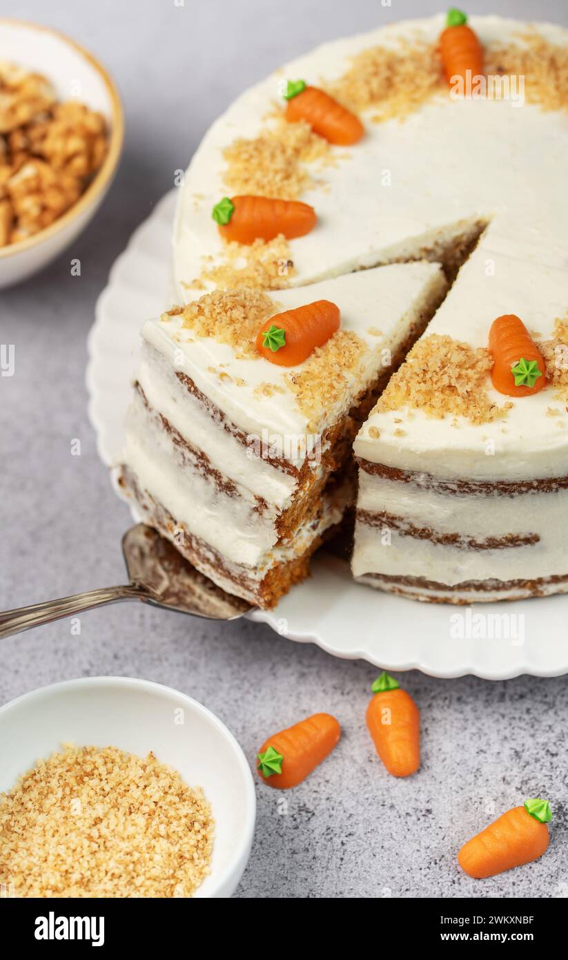 Torta di carote fatta in casa con noci, ghiacciata con formaggio spalmabile. Dolce dolce. Piatto con deliziosa torta di carote Foto Stock